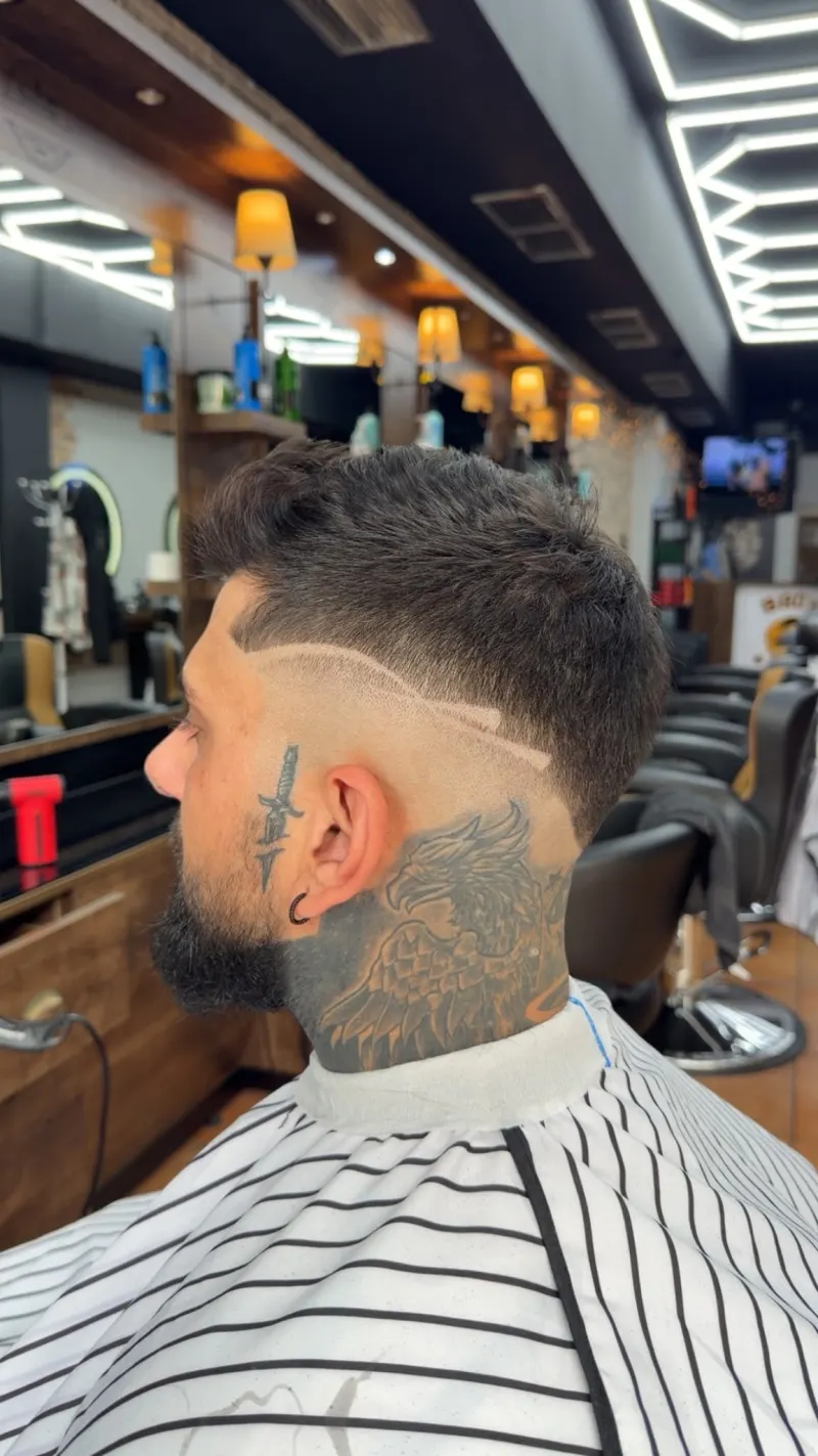 Herrenhaarschnitt bei Bro’s Barbershop Hamm: Low Fade mit rasierter Designlinie, präzisen Konturen und geformtem Bart